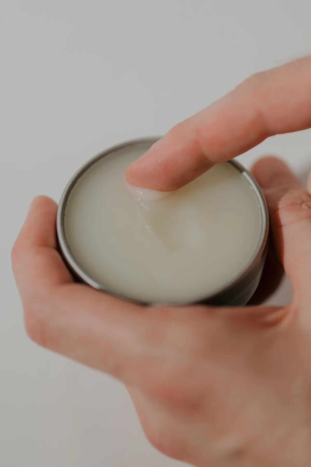 A finger lifting Barrier Balm from the open tin