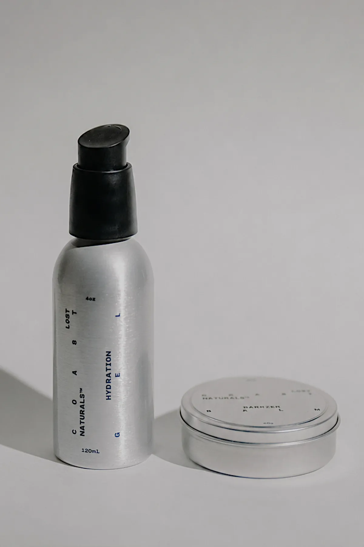 The Hydration Gel bottle standing beside the Barrier Balm tin